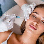 Young woman gets beauty facial injections in clinic