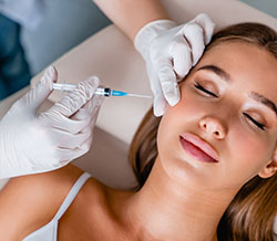 Young woman gets beauty facial injections in clinic