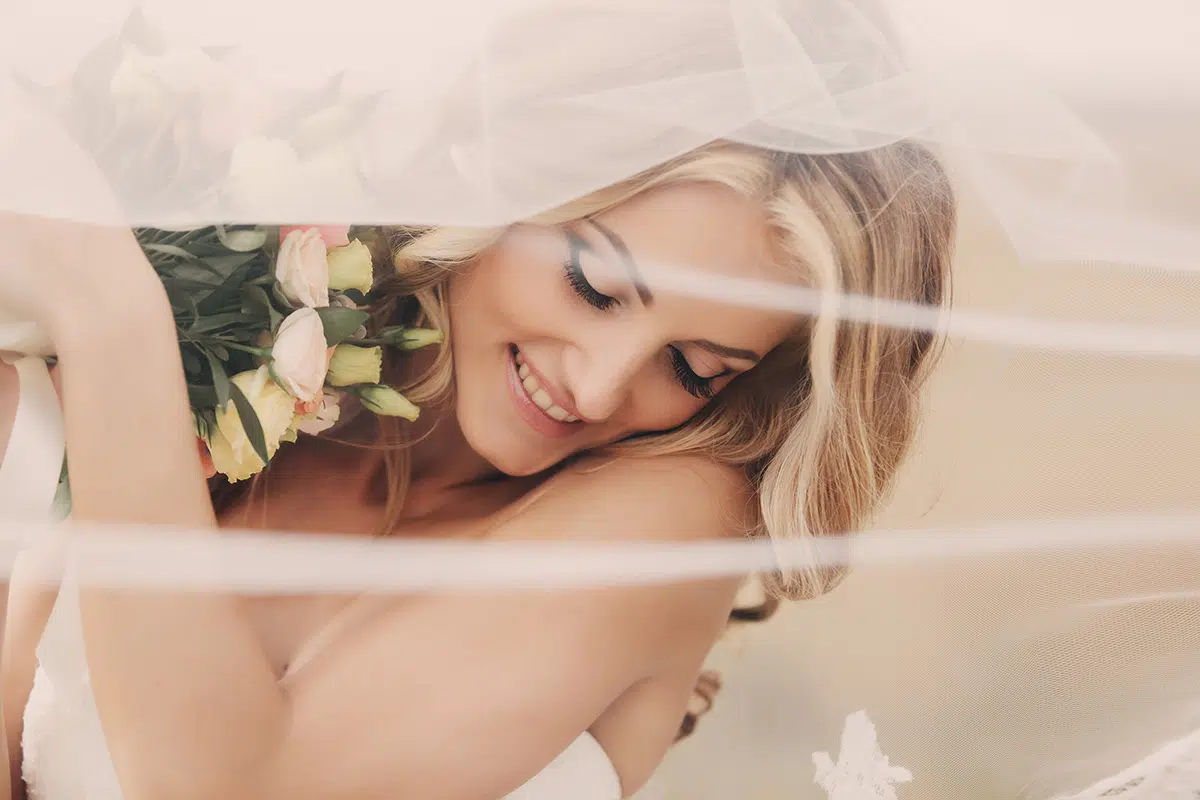 beautiful blonde bride with a bouquet of flowers ith wedding makeup and hairstyle