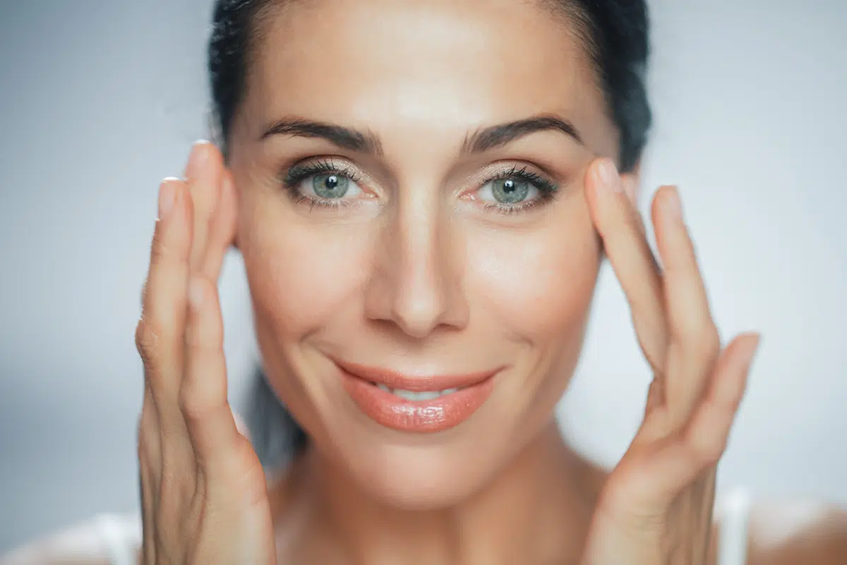 beautiful caucasian woman touches her perfect face with soft skin