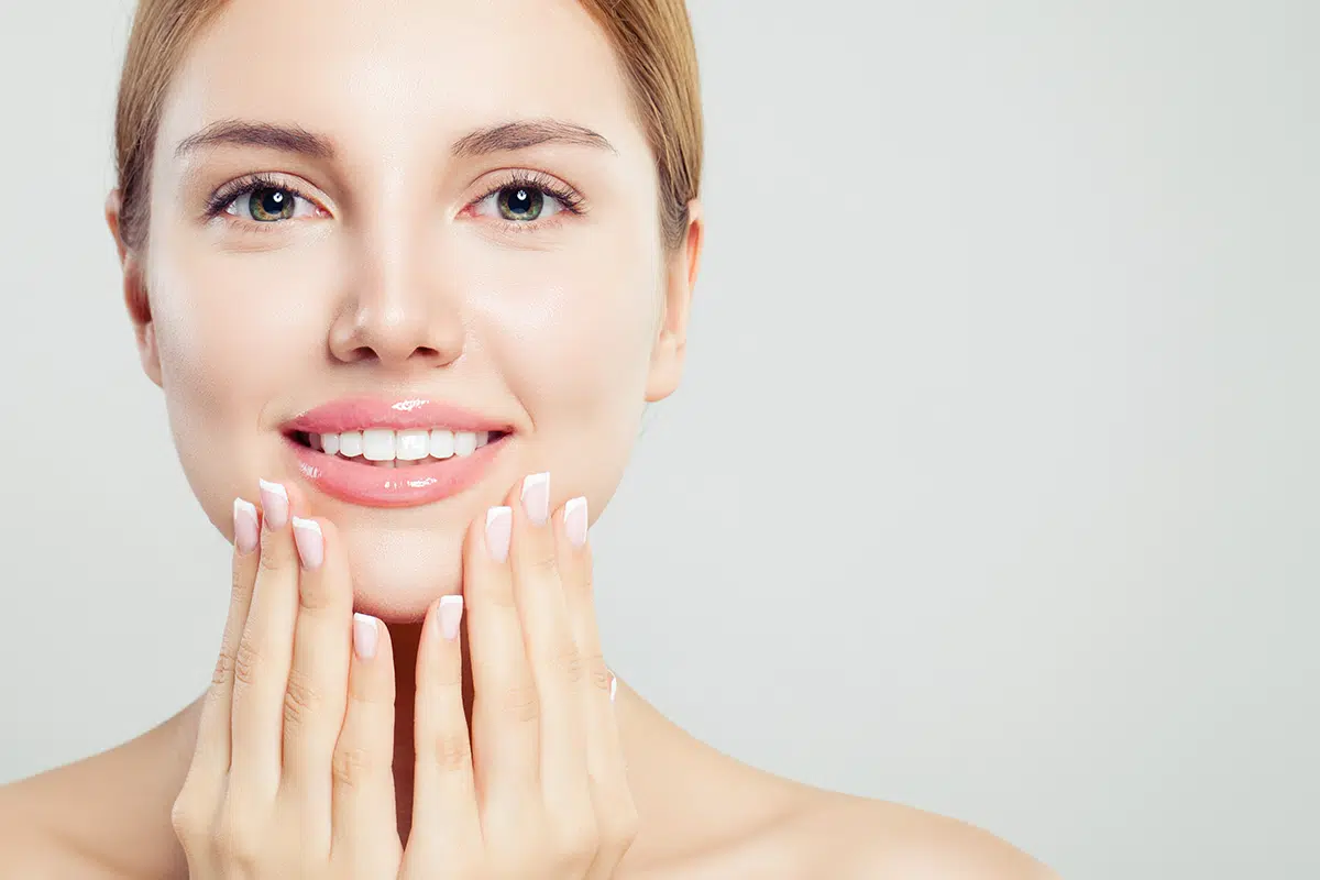 beautiful face with pink glossy lips and manicured hands with french manicure nails