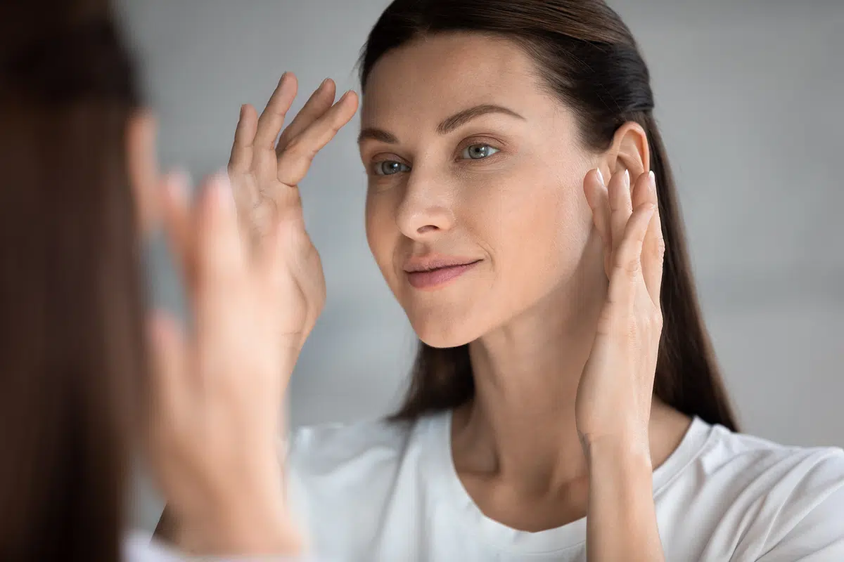 beautiful woman with perfect skin looking in mirror