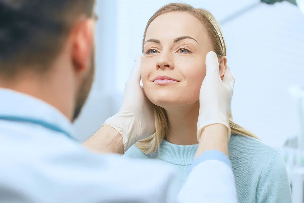 cosmetic surgeon examines beautiful woman s face