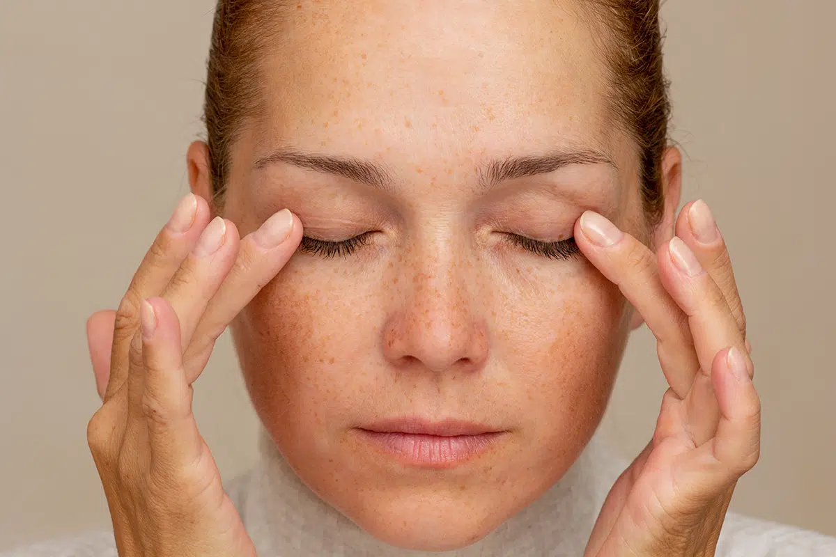 middle aged caucasian woman with closed eyes holding fingers on eyelids to show eyes aging