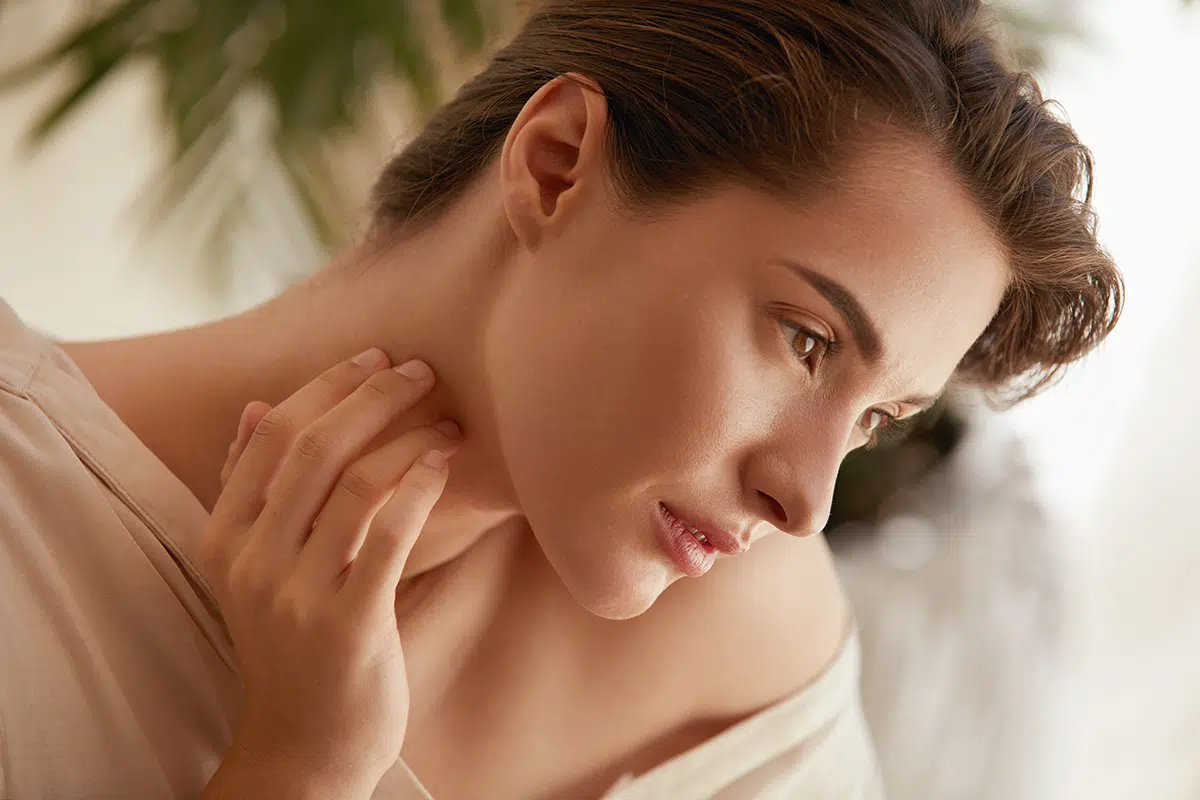 woman touching neck and looking away