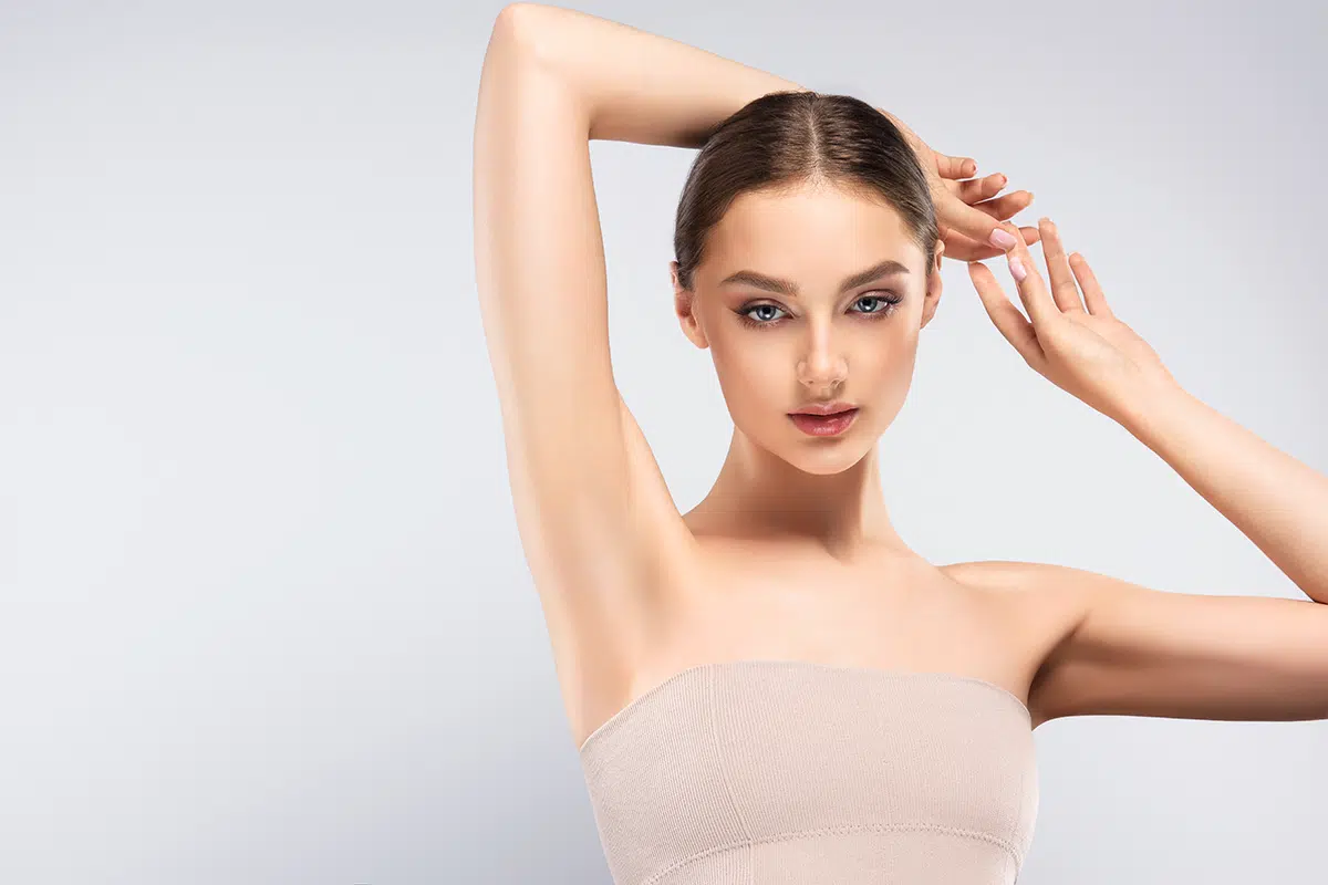 young woman holding her arms up and showing clean underarms